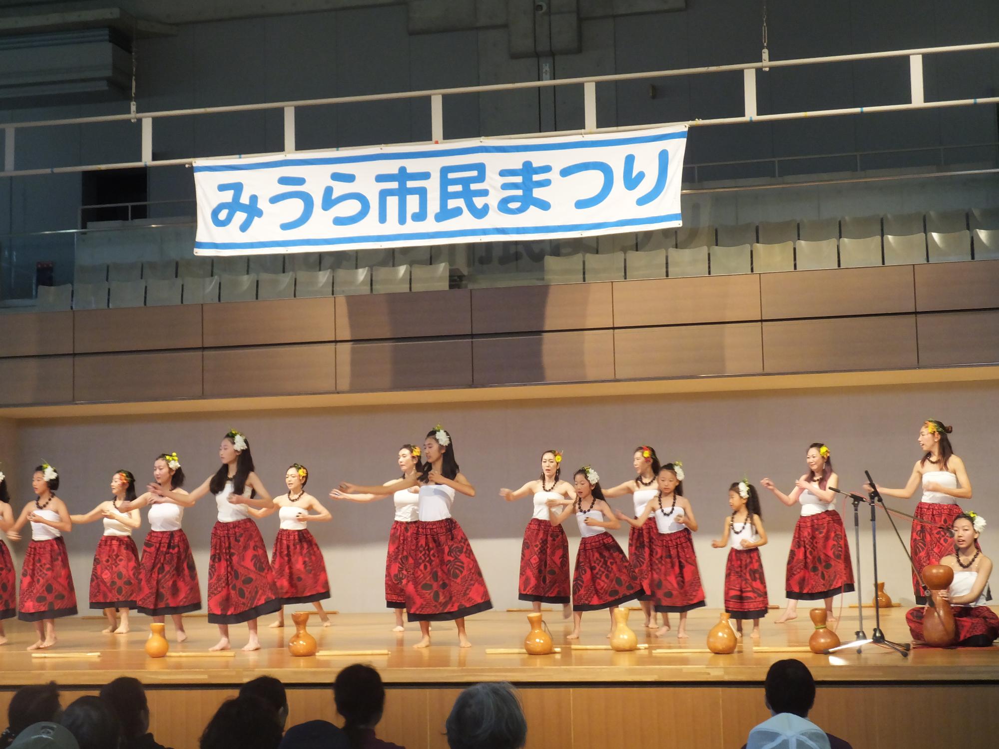 屋内ステージでフラダンスを披露する市民の方々