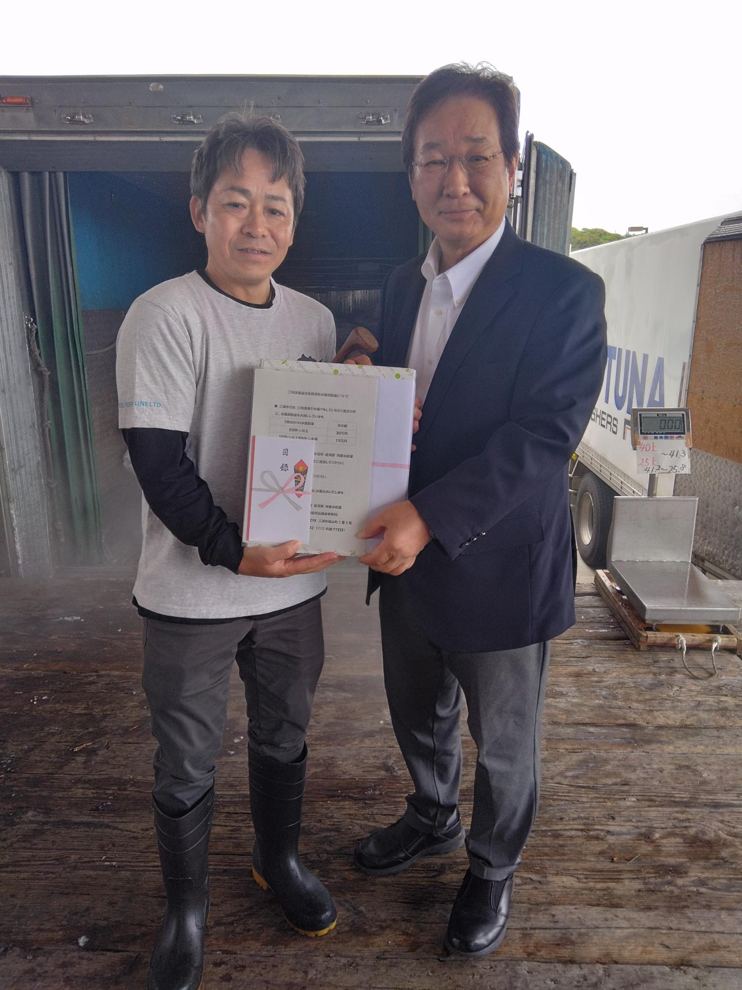 記念品を持った男性二人が並んでいる写真