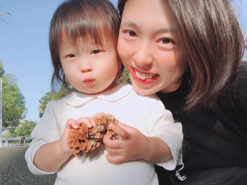 松ぼっくりを持った小さな娘と一緒に写っている母親の写真