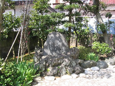 多くの木が植えられた庭に石碑が置かれている写真