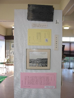 柱の一つの面に、解説文や写真などの資料が並べて展示されている写真