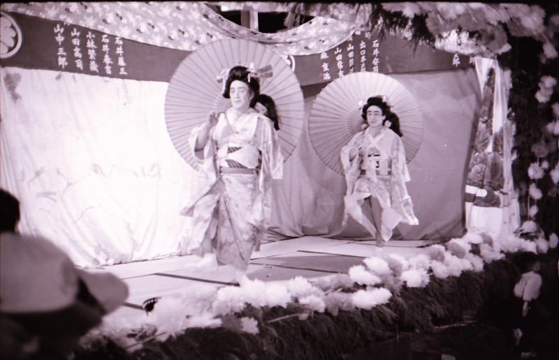 着物を着た女性2人が唐傘を持って踊っているセピア調の写真