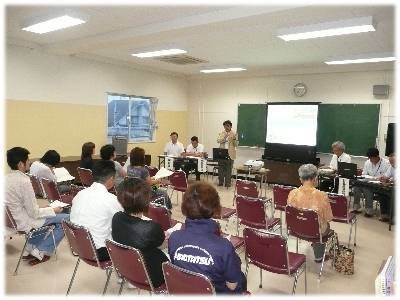 三崎中学校の会議室で、椅子を並べて座り目の前のスクリーンを見ながら意見書の説明を受けている人々の写真