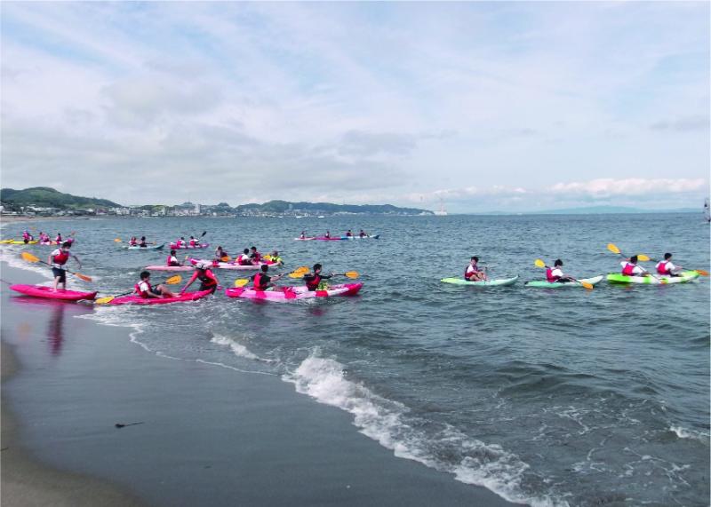 浜辺から、生徒たちが乗っているカヌーが並んで漕ぎ出している写真