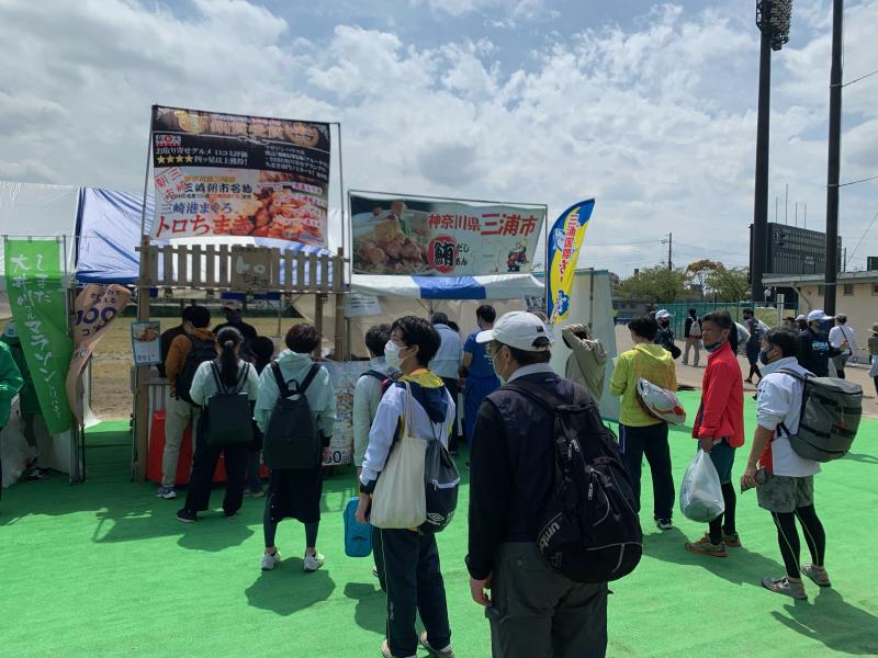三浦市のブースで販売されている「三崎まぐろラーメン」「三崎港まぐろトロちまき」などを目当てに人々が並んでいる写真