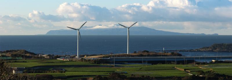 海に向かって、2本の大きな風車が並んでいる写真