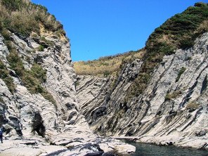 切り立った崖の谷間に川が流れている風景の写真