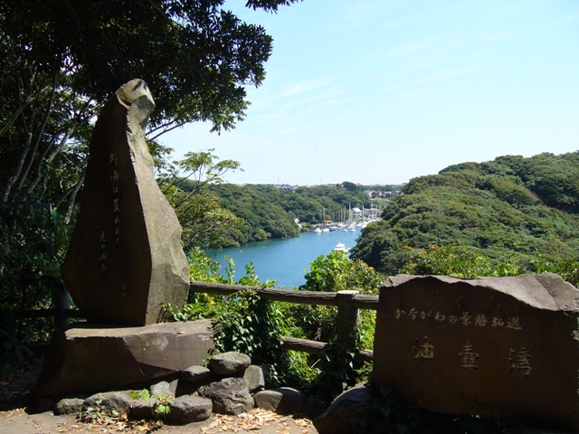 2つの石碑から山林に囲まれた入江が見える写真