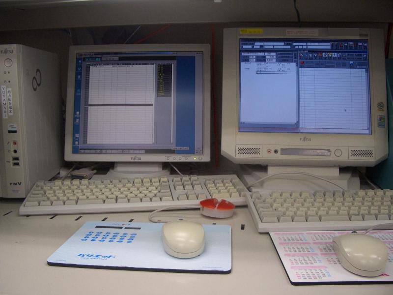 モニターにシステムが表示されているパソコンが2台並んでいる机の写真