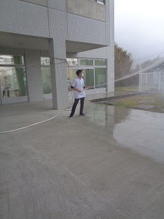 建物の外で、男性がホースから放水している写真