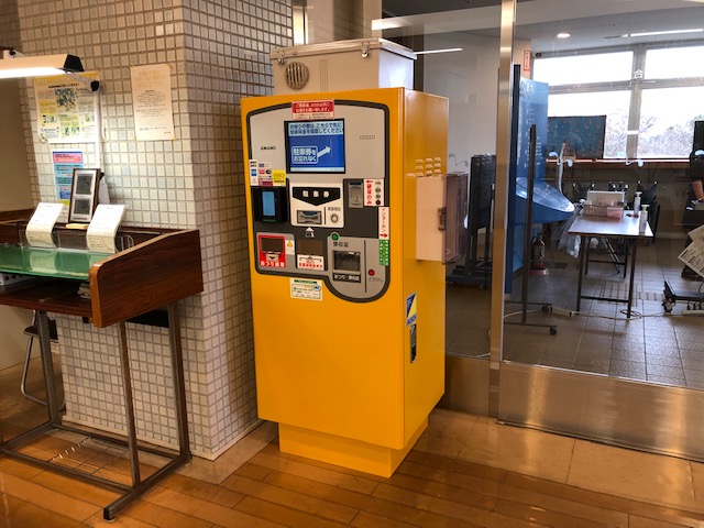 室内の出入り口ドア付近に置かれた黄色の精算機の写真