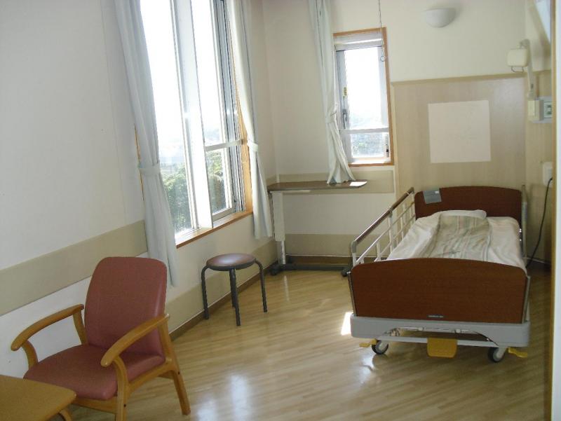 ベッドが一台とテーブルと椅子が置かれた広い病室の写真