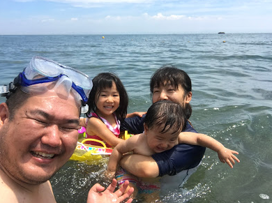 家族四人で笑顔で海水浴を楽しんでいる写真