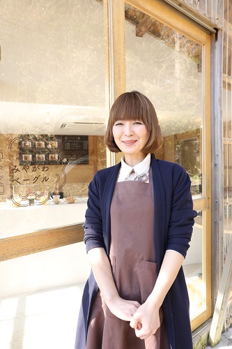 お店の前でエプロンを付けて笑顔で立っている蛭田奈奈さんの写真