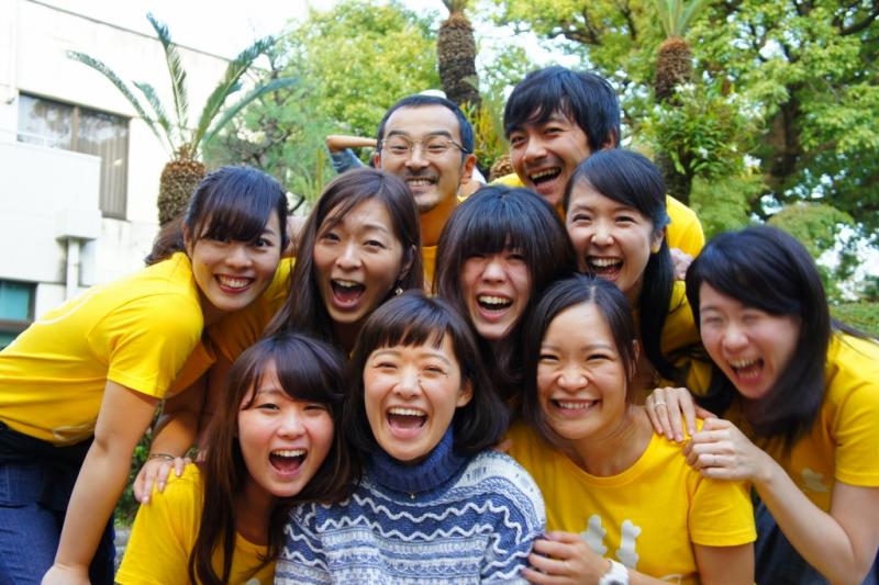満面の笑顔で集まっている黄色いTシャツを着た人たちの写真