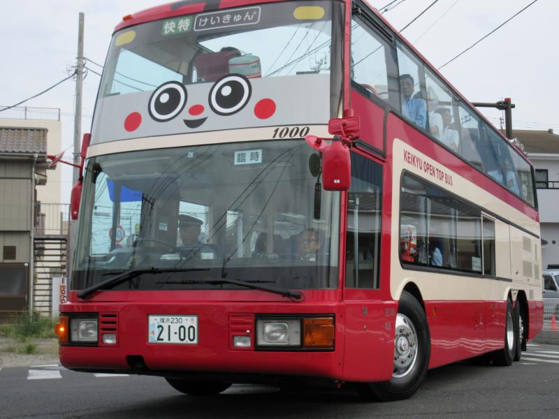 顔がプリントされた赤い2階建て観光バスの写真
