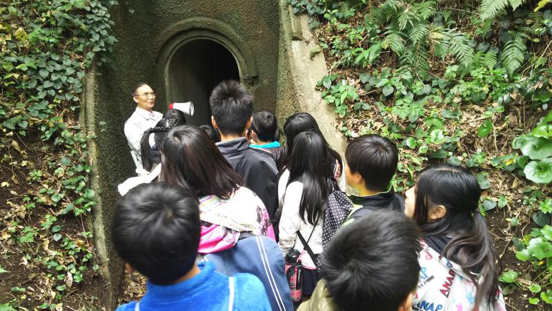 地下壕入り口で説明を受ける子供たちの写真