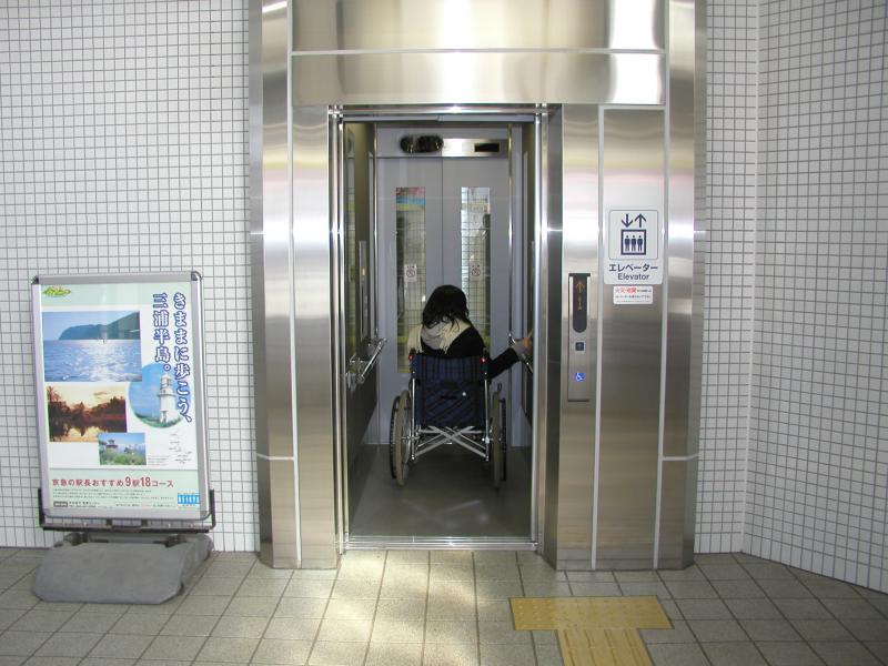銀色のエレベーターの中に、車椅子に乗った人物が入っている写真
