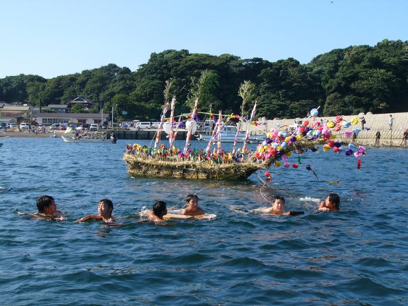 海に浮かんだ藁の船と泳ぐ人たちの写真