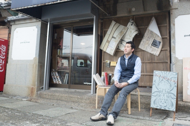 尼野さんが玄関前で椅子に腰かけている写真