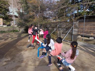 公園に設置されたシーソーの両側に、子供たちが乗って遊んでいる写真